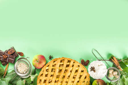 Autumn cooking baking background with sweet apple pie. Traditional american apple pie with fresh apples, cinnamon, spices, baking ingredients, top view copy space on light green backgroundの写真素材