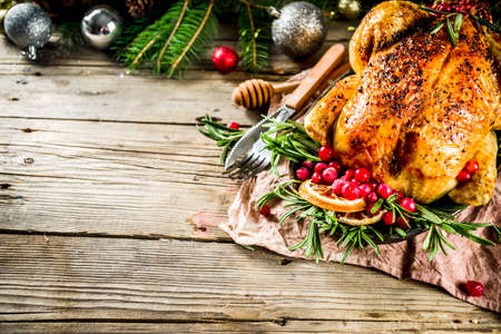 Traditional Christmas and Thanksgiving roasted whole chicken with fruit and rosemary. Rustic wooden christmas table, with xmas tree branches and decorations copy spaceの写真素材