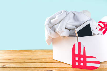 Donation Box with various give goods for Giving Tuesday, with red heart logo. Charity. Collect unwanted waste goods, pass it poor needy people concept. Participating in international donation drive.の写真素材