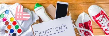 Donation Box with various give goods for Giving Tuesday, with red heart logo. Charity. Collect unwanted waste goods, pass it poor needy people concept. Participating in international donation drive.の写真素材