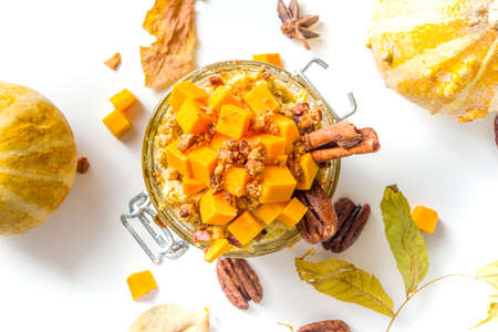 Autumn pumpkin pecan oatmeal, overnight oats porridge with butternut squash slices, pecan nuts and caramel sauce, white wooden background copy spaceの写真素材
