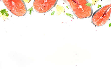 Set of fresh ready for cooking raw salmon steaks, red fish portioned slices with salt and spices, on white table background top view copy spaceの写真素材