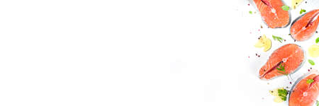 Set of fresh ready for cooking raw salmon steaks, red fish portioned slices with salt and spices, on white table background top view copy spaceの写真素材