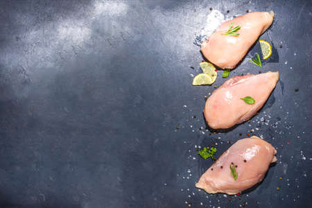 Raw chicken breast filet on dark concrete background with spices and herbs for cooking, top view copy spaceの写真素材