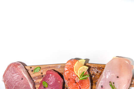 Various natural food, high animal protein sources - pork, beef meat steaks, chicken breast fillet, eggs, salmon fish on white table background top view copy spaceの写真素材