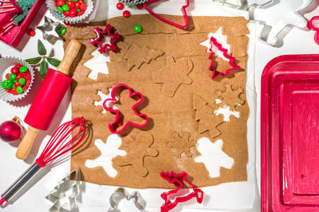 Christmas, New Year cooking background. Baking ingredients and utensils - gingerbread dough, cookie cutters, rolling pin. Making festive Christmas sweet cookies bright festive red white conceptの写真素材