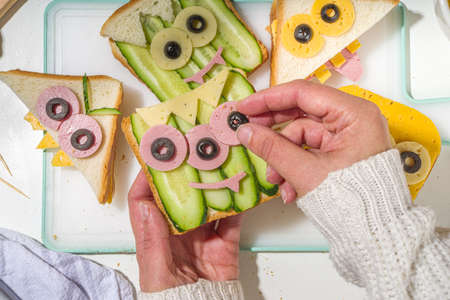 Various funny monster Halloween sandwiches. Cooking creative breakfast snack toasts with cheese, Halloween kids party food, mother woman hands in picture top viewの写真素材
