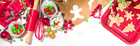 Christmas, New Year cooking background. Baking ingredients and utensils - gingerbread dough, cookie cutters, rolling pin. Making festive Christmas sweet cookies bright festive red white conceptの写真素材