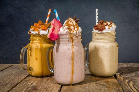 Apple pumpkin and pecan pie smoothie drinks. Traditional autumn baking cake flavor cocktails set, on dark wooden background copy spaceの写真素材