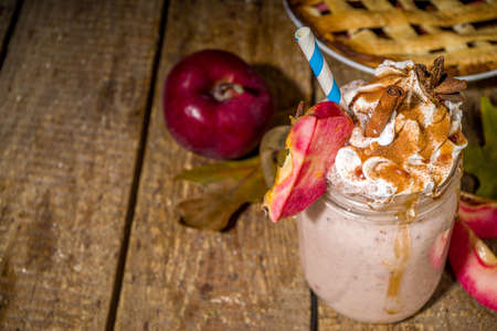 Apple pie smoothie. Crazy shake cocktail with traditional autumn apple pecan flavor, wooden dark background copy spaceの写真素材