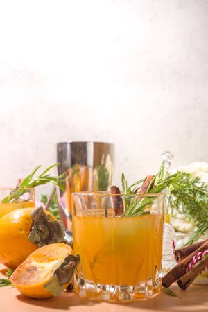 Autumn alcohol drinks. Spicy boozy gin persimmon cocktail with rosemary and cinnamonの写真素材