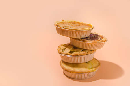 Set variety autumn pies. Pecan, apple, pumpkin small tart cakes and pies on concrete background with bright sun light, dark shadows top viewの写真素材