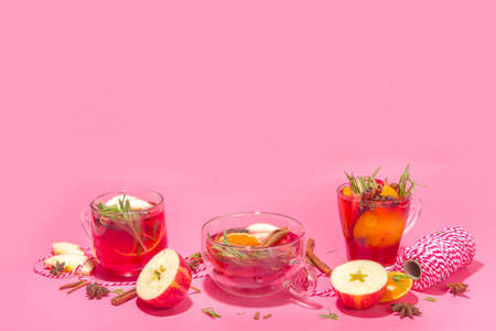 Homemade mulled wine cocktail. Various glass mugs with classic winter hot spicy mulled wine, with ingredients, Christmas decor and gift boxes on high-colored modern backgroundの写真素材