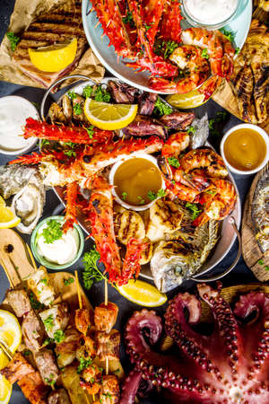 Assortment various barbecue Mediterranean grill food - fish, octopus, shrimp, crab, seafood, mussels, summer diet bbq party fest, with kebab, sauces, black concrete background, above copy spaceの写真素材