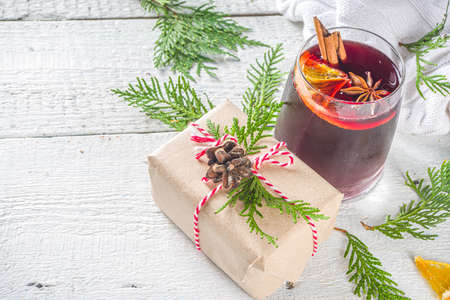 Festive Composition with Paper Craft Gift Box and Mulled Wine Glass, on wooden table with Christmas Fir Tree. Happy New Year and Christmas Greeting Card background adventの写真素材