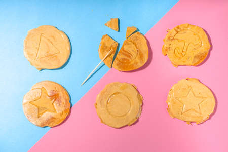 Worldwide Craze Trending Game, Squid Game TV Series, Korean Cookies - Dalgona Sweets Candy Challenge, on bright high-colored pink blue background flat lay top viewの写真素材