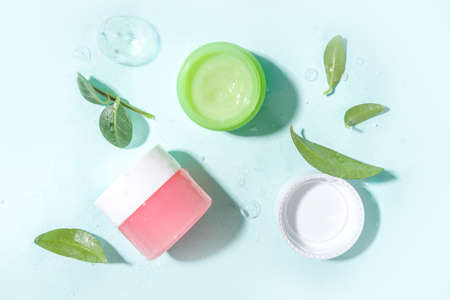 Cosmetic bottle with water drops, bubbles and green leaves. Moisturizing, Facial Care, reparing and skincare product. Top view flaylay copy spaceの写真素材