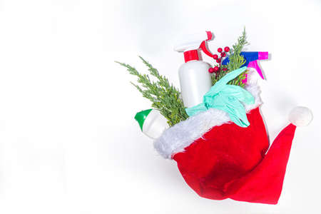Christmas cleaning concept. Various bottles, equipment, and accessories, gloves for cleaning with christmas decor and santa hat copy space. Cleaning service advertising mockup backgroundの写真素材