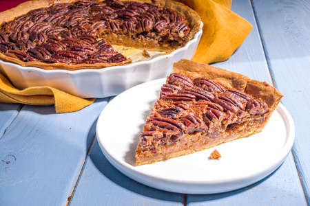 Thanksgiving dinner table with new traditional thanksgiving food - chicken, mashed sweet potatoes, green beans, pecan pie, baked ham pork, mac and cheese, stuffing, modern hard sunny light flatlayの写真素材