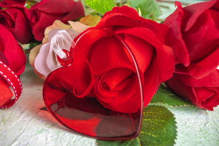Valentine's Day, Birthday, Mother's Day Festive greetings card background. Big bouquet of white, red roses with a beautiful red glass heart pendant, gift box with a ribbon bow, on a light green backgroundの写真素材