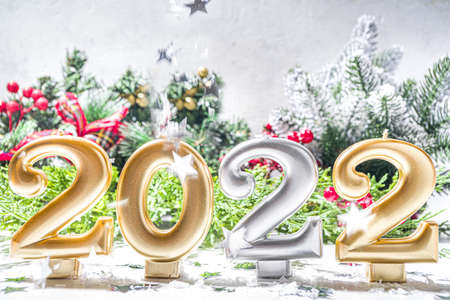 2022 new year greeting card background, festive banner with 2022 holiday candles, silver star decor, christmas tree branches and artificial snowの写真素材