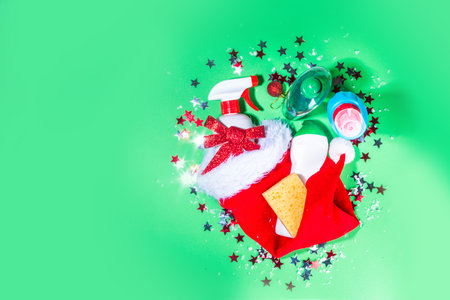 Christmas cleaning concept. Various bottles, equipment, and accessories, gloves for cleaning with christmas decor and santa hat. Cleaning service advertising mockup backgroundの写真素材