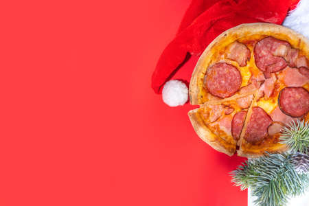Christmas decorated background with pepperoni and mushrooms pizza, Delivery and restaurant Xmas Lunch and party menu, Santa delivers pizza for Christmas, white red modern high-colored backgroundの写真素材