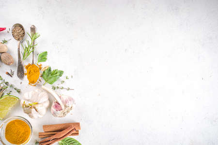 Fresh herbs, dried colorful spices. Cooking background flatlay with variety spices, herbs pepper, vanilla bean, cinnamon, basil, rosemary, chilli red green peppers, mint, parsley White table top viewの写真素材