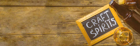 Craft spirit alcohol. Various bottles and glass with hand crafted hard strong alcohol drinks. Old wooden rustic background copy spaceの写真素材