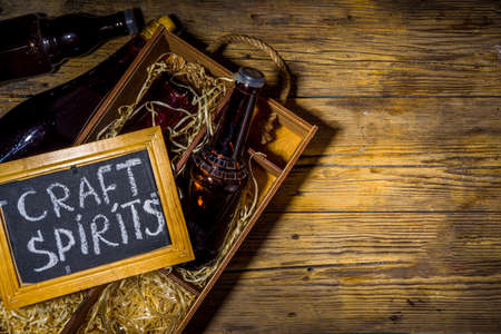 Craft spirit alcohol. Various bottles and glass with hand crafted hard strong alcohol drinks. Old wooden rustic background copy spaceの写真素材