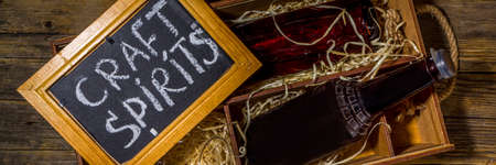 Craft spirit alcohol. Various bottles and glass with hand crafted hard strong alcohol drinks. Old wooden rustic background copy spaceの写真素材