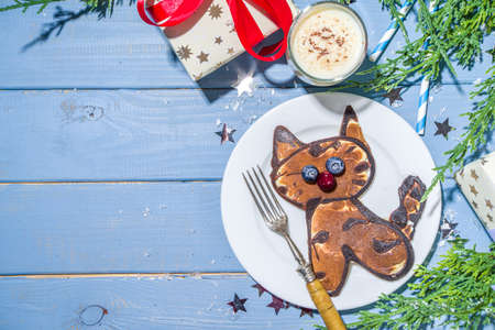 Christmas New Year morning breakfast, kids festive brunch snack. Funny tiger pancakes, creative New Year 2022 symbols pancakes made with berries, chocolate and vanilla doughの写真素材