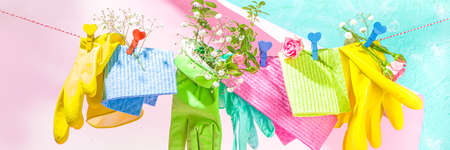 Creative bright spring cleaning concept. Tools, bottles, accessories for cleaning house with spring flowers and leaves hang on clothesline, box, bright sunny light copy spaceの写真素材