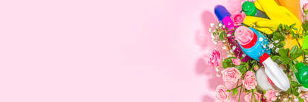 Creative bright spring cleaning concept. Tools, bottles, accessories for cleaning house with spring flowers and leaves hang on clothesline, box, bright sunny light copy spaceの写真素材