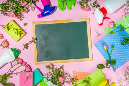 Creative bright spring cleaning concept. Tools, bottles, accessories for cleaning house with spring flowers and leaves hang on clothesline, box, bright sunny light copy spaceの写真素材