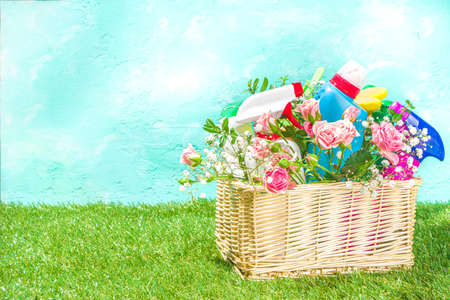 Creative bright spring cleaning concept. Tools, bottles, accessories for cleaning house with spring flowers and leaves hang on clothesline, box, bright sunny light copy spaceの写真素材