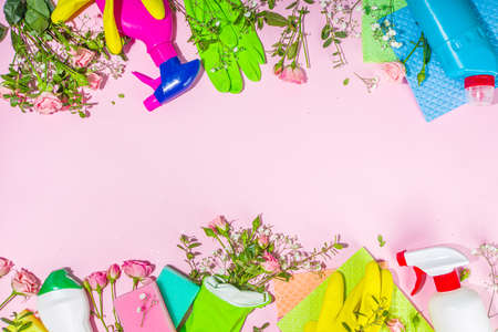 Creative bright spring cleaning concept. Tools, bottles, accessories for cleaning house with spring flowers and leaves hang on clothesline, box, bright sunny light copy spaceの写真素材