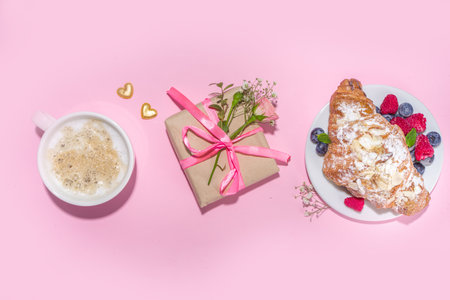 Croissant with coffee and Valentines gift and coffee latte mug on pink background copy space. Valentine day, Mother day sweet tasty breakfast idea. Good morning and nice spring, summer day conceptの写真素材