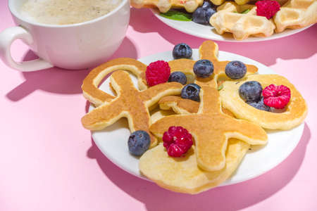 Valentine day brunch menu background with various breakfast and lunch dishes, waffle, growing, muffins, donuts, berries, fries scrambled eggs, pancakes, pink background copy spaceの写真素材