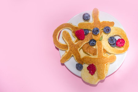 XOXO shaped Valentines pancakes, with berry and coffee latte mug on pink background copy space. Valentine day sweet tasty breakfast ideaの写真素材