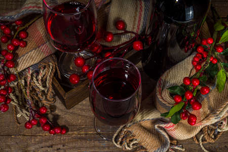 Winter wine tasting degustation background. Craft wine bottle with two glasses over wooden background with cozy plaid and winter decoration copy spaceの写真素材