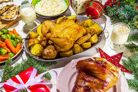 Festive Christmas dinner table with traditional foods and dished - baked ham, chicken, roasted carrots and brussels sprouts, potato, with Christmas decor and giftsの写真素材