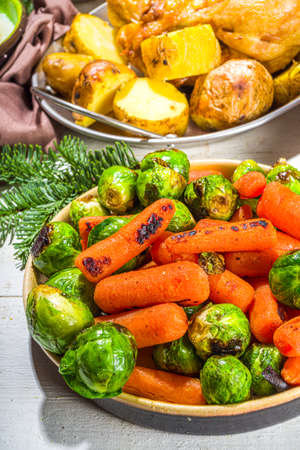 Festive Christmas dinner table with traditional foods and dished - baked ham, chicken, roasted carrots and brussels sprouts, potato, with Christmas decor and giftsの写真素材