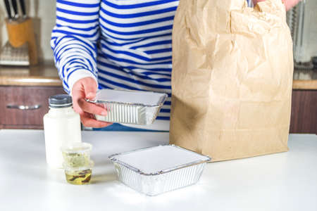 Caucasian woman take apart package with Heat-and-eat meal boxes from the restaurant. Takeout order...