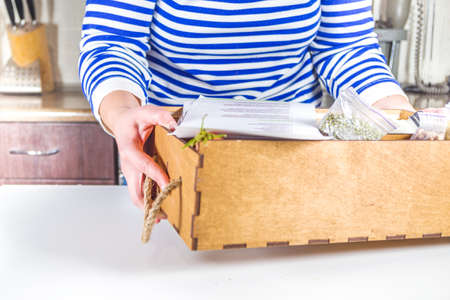 Caucasian woman take apart box with delivery of ingredients, recipes. Meal Kit Delivery Concept. Set various healthy foods with recipes for cooking. Online ordering of restaurant chef grocery deliveryの写真素材