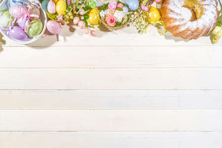 Easter painted colorful pastel eggs in a basket, with feathers on a light wood background. Easter greeting card composition, spring holiday still life backgroundの写真素材