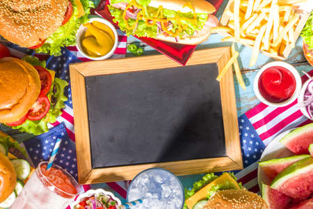 Fourth of July, Memorial Day, USA Independence Day concept. Patriotic, American traditional food. Picnic party with watermelon, burgers, hot dogs, drinks, blue wooden outdoor table backgroundの写真素材