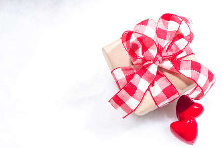 Valentine's Day holiday background. Craft paper gift box with ribbon, rose flowers and hearts decor,...