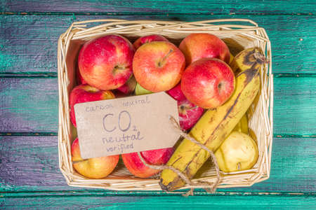 Carbon neutral, CO2-free concept product. Natural organic farm fruit apples, with CO2 neutral tag verified, on wooden desk in farm storeの写真素材