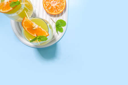 Classic summer mimosas cocktail, with orange juice, on light blue background. Summer bar menu...